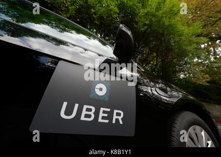 Una Volkswagen nera con il logo Uber è usato come un taxi e mostra anche un driver in una verdeggiante strada suburbana NEL REGNO UNITO (solo uso editoriale). Foto Stock