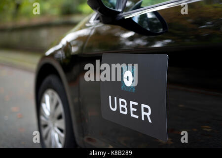 Una Volkswagen nera con il logo Uber è usato come un taxi e mostra anche un driver in una verdeggiante strada suburbana NEL REGNO UNITO (solo uso editoriale). Foto Stock