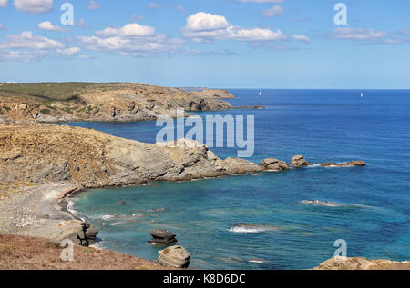 Vista costiera sull isola delle Baleari di Minorca nel mar mediterraneo con barche a vela in distanza Foto Stock