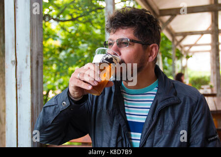 Grave uomo barbuto ceca bere birra locale sulla terrazza ristorante Foto Stock