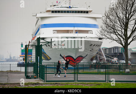 Il rosso lipsticked Aida Cara nave da crociera nel Porto a Southampton docks si affaccia a uomini giocare a basket Foto Stock