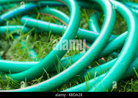 Un verde e arancione il tubo flessibile per innaffiare il giardino vicino fino Foto Stock