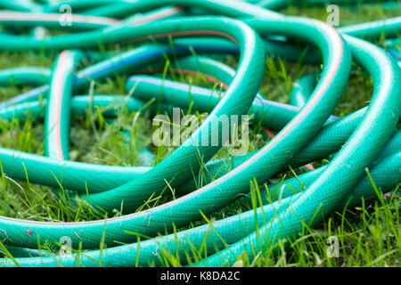 Un verde e arancione il tubo flessibile per innaffiare il giardino vicino fino Foto Stock