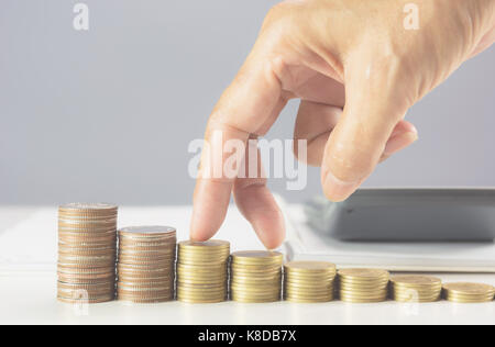 Mano camminando sulla pila di monete sul tavolo. Finanziaria e la crescita del business del concetto. Foto Stock