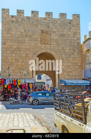 Monastir, Tunisia - agosto 29, 2015: la medievale Porta di pietra fortificata medina, le bancarelle dei souk locale (bazar) stand strettamente alla parete, il ago Foto Stock