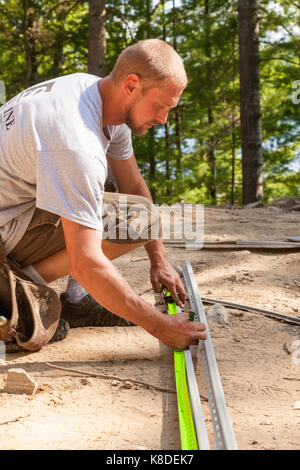 Un lavoratore edile di marcatura di bordatura in vinile utilizzando una matita e una misura di nastro in Ontario, Canada. Foto Stock