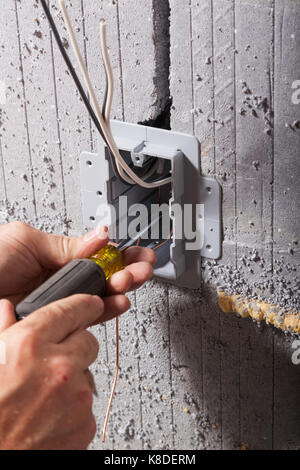 Un elettricista che fissano un quadro elettrico di utility box utilizzando un cacciavite isolato in forma concreta in Ontario, Canada. Foto Stock