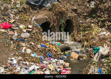 Il drenaggio delle tubazioni di scarico acqua vuoto nel villaggio di Ngong fiume che è inquinata con rifiuti, rifiuti in plastica e spazzatura, Nairobi, Kenia Foto Stock