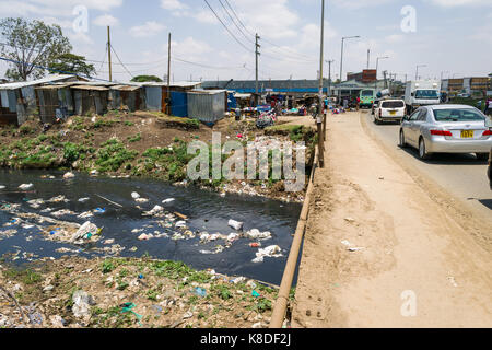 Enterprise ponte stradale attraversa il Ngong fiume che è inquinata con rifiuti, rifiuti in plastica e spazzatura, baracche baraccopoli lungo il fiume, Nairobi, Kenia Foto Stock