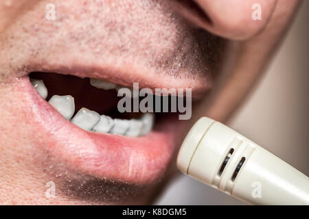 La parte inferiore della faccia stretta di un uomo parlando in un microfono. Foto Stock