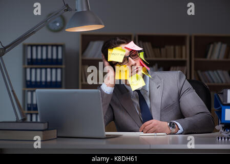 Uomo d'affari che soggiornano in ritardo per ordinare le priorità Foto Stock