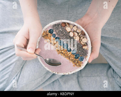 Mangiare sano colazione ciotola. Frullato di grano saraceno porrige, frutti di bosco freschi, semi e noci, polline di api in ceramica bianca ciotola in mani donna. Pulire eatin Foto Stock