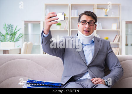 L'uomo nel rinforzo del collo collare cervicale lavorando da casa il telelavoro Foto Stock