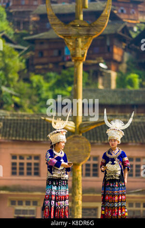 Xijiang, Cina - 15 Settembre 2007: due appartenenti a una minoranza etnica Miao donne che indossano abiti tradizionali e di acconciatura di argento stand presso piazza cittadina di palo in legno Foto Stock