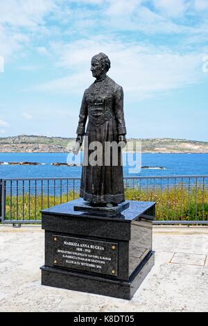 Statua di markiza anna bugeja sul fronte mare con vedute di St Pauls Bay, Bugibba, Malta, l'Europa. Foto Stock