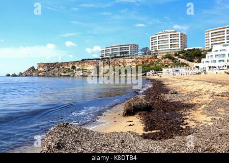 Vista lungo la spiaggia verso gli hotel on the cliff tops, Golden Bay, Malta, l'Europa. Foto Stock