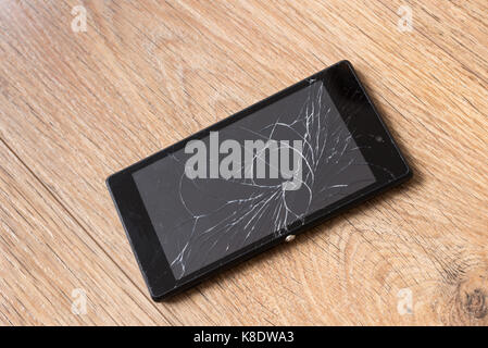 Smartphone rotto, su sfondo di legno Foto Stock