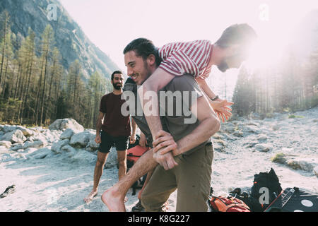 Giovane uomo che porta un amico sulla spalla su Riverside, lombardia, italia Foto Stock