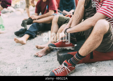 Collo in giù in vista dell adulto bouldering amici mettendo su calze e formatori, lombardia, italia Foto Stock