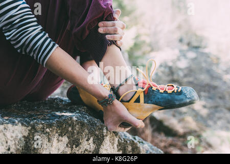 Vita scende di boulderer femminile mettendo sul pattino di arrampicata, lombardia, italia Foto Stock