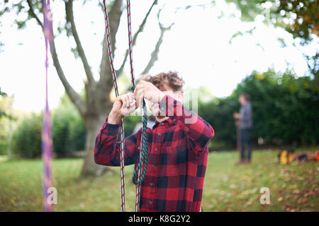 Partecipante teenage albero maschio chirurgo preparazione di arrampicarsi sulle funi Foto Stock