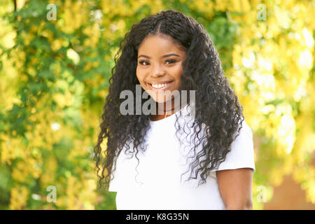 Ritratto di capelli ricci ragazza adolescente guardando sorridente della fotocamera Foto Stock