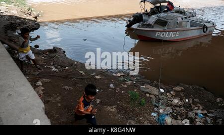 Childreb Gioca in spazzatura e Cestino vicino a una pattuglia di polizia sotto il ponte di Monivong sul fiume Bassac a Phnom Penh Cambogia Foto Stock