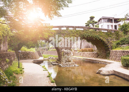 Mattoni vecchio ponte che attraversa il fiume con la luce del sole. Foto Stock