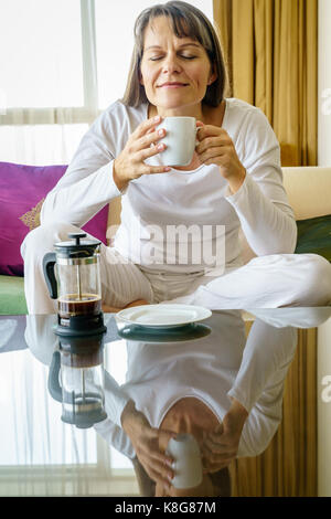 Donna matura è godendo del caffè fresco la mattina Foto Stock