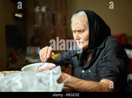 Vecchia donna rurale di mangiare la sua zuppa da una ciotola Foto Stock