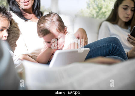 La famiglia gioca con tavoletta digitale sul divano Foto Stock