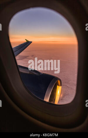 Sunset cloudscape e ala di aeroplano attraverso la finestra di aeroplano Foto Stock