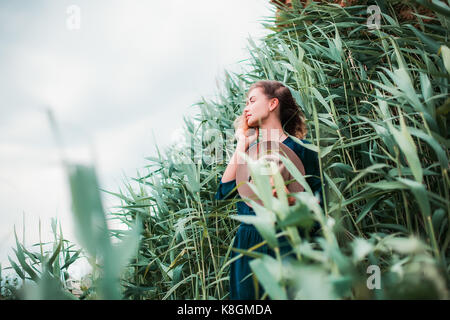 Metà donna adulta accanto a erba lunga, toccando i capelli e respirare aria fresca Foto Stock