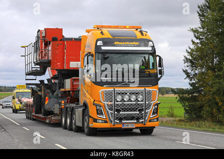 Koski tl, Finlandia - agosto 15, 2017: giallo volvo fh16 Carrello semi di cale rantala mantsinen 50 macchina di movimentazione materiale come carico oversize lungo highw Foto Stock