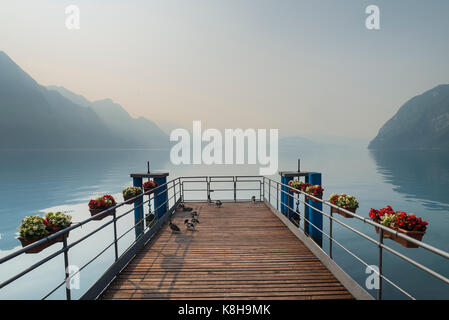 Abbandonato il dock del traghetto di Riva di Solto sporge nella calme acque del lago d'Iseo in una soleggiata mattinata estiva, lombardia, italia Foto Stock