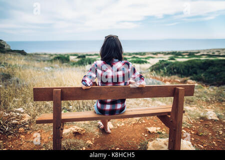 La donna gode di vista mare seduta su una panchina nella bellissima valle. Concetto di relax Foto Stock