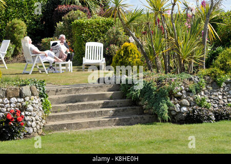 Un vecchio o coppia di mezza età relax al sole estivo in un bellissimo giardino in un hotel sull'Isola di Wight a Shanklin. Foto Stock