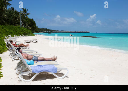 Maldive beach - i turisti a prendere il sole sulla spiaggia a Kuramathi resort hotel, Maldive, Asia Foto Stock