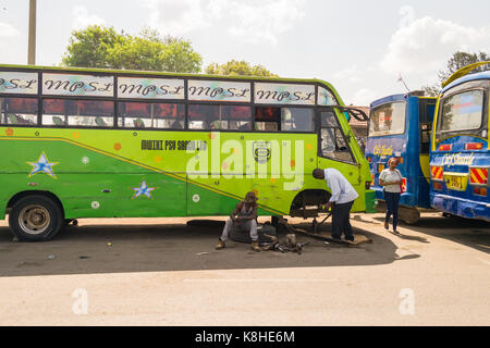 Due uomini bus di fissaggio ruota e assale da strada, Nairobi, Kenia Foto Stock