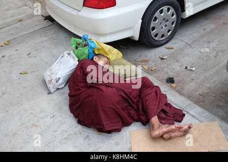 La birmania, myanmar: Monk dormire in una strada di Rangoon Foto Stock