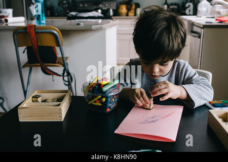 Ragazzo giocando con il timbro di gomma a casa Foto Stock