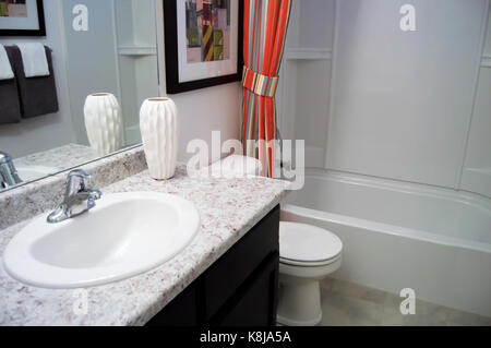 Una piccola stanza da bagno con un bancone di marmo e un lavabo cromata con un acent di red striped tende da doccia. Foto Stock