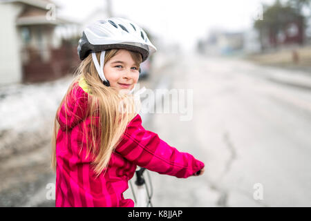 Bambina in sella a una moto in una città Foto Stock