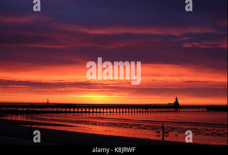 Il fuoco come il cielo all'alba sopra il porto di blyth sulla costa di Northumberland. Foto Stock