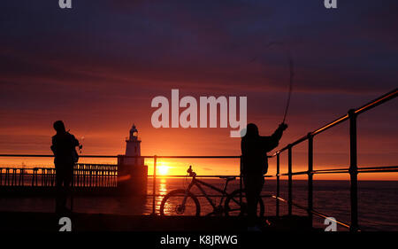 Pescatore sul molo di blyth sulla costa di northumberland all'alba. Foto Stock