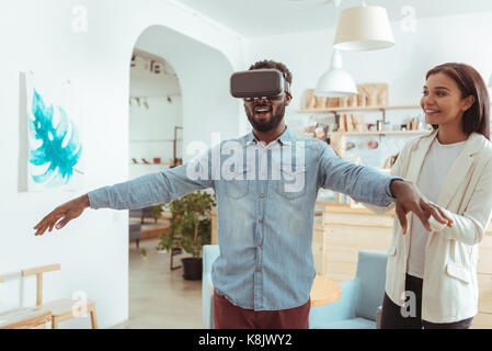 Upbeat man provando le nuove cuffie vr in cafe Foto Stock