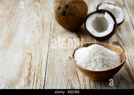 Cocco grattugiato nella ciotola con il suo guscio in background Foto Stock