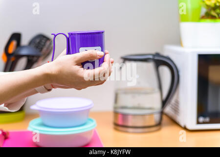 Tenere le mani una tazza di plastica con il volto sorridente Foto Stock