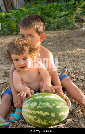 Fratello e Sorella in seduta il prato con cocomero gigante Foto Stock