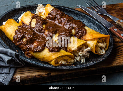 Cucina messicana. Tradizionale messicano enchiladas di pollo con cioccolato speziato salsa mole poblano. Enchiladas con salsa moole da Puebla, Messico. Foto Stock